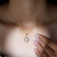 a close up of a person wearing a necklace with a diamond pendant on their chest