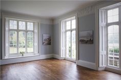 an empty living room with wood floors and white trim on the walls, two large windows