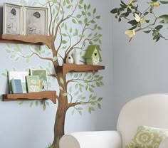 there is a tree with books on the shelves in this room, and two birds are perched on it