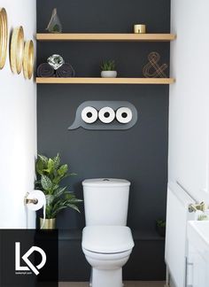 a white toilet sitting in a bathroom next to a wall mounted shelf filled with plates