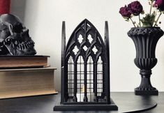 a gothic - inspired candle holder sits on a table next to some books and skulls