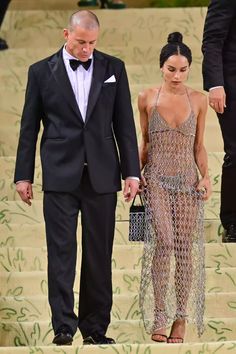 a man in a tuxedo and a woman in a dress walking down stairs