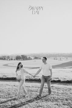 a man and woman holding hands while walking across a field with the words happy day written on it