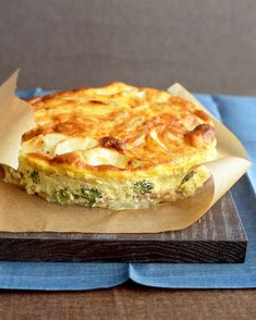 a quiche with cheese and spinach is sitting on a piece of wax paper