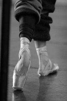 black and white photograph of someone's feet in ballet shoes on the dance floor