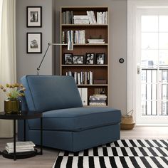 a living room with a gray chair and bookshelf in the corner, next to a black and white striped rug