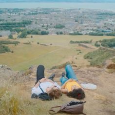 two people laying on top of a hill