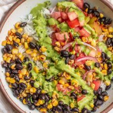 a bowl filled with black beans, corn and guacamole