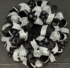 a black and white christmas wreath with snowflakes on the front door, hanging on a brick wall