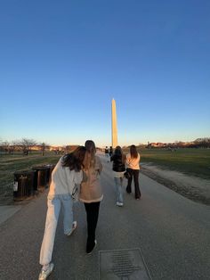 three girls are walking down the road near the washington monument