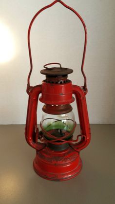 an old fashioned red oil lamp on a table