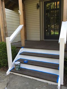 the steps are painted white and brown with blue tape on them, along with a can of paint