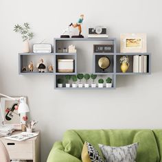 a green couch sitting in front of a white wall with shelves on it's sides