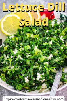 lettuce dill salad in a white bowl with lemon wedges