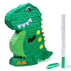 a paper sculpture of a green dinosaur next to a toothbrush