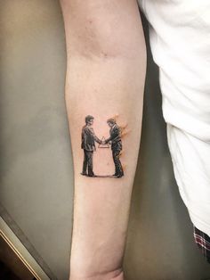 a person with a tattoo on their arm shaking hands next to another person's leg