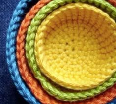 three crocheted bowls in different colors on top of each other, with one yellow and the other blue