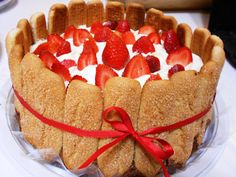 a cake with strawberries and whipped cream on top is sitting on a glass plate