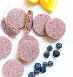 blueberries and lemons are next to soap bars on wax paper with one cut in half