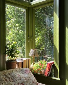 a bedroom with green walls and plants in the window sill, next to a bed