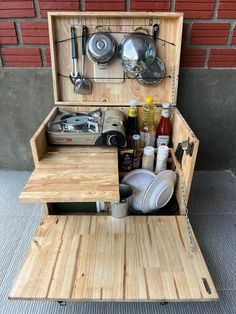 an open wooden box filled with cooking utensils and other kitchen items on top of a table