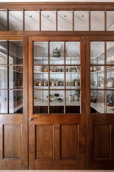 a kitchen with wooden doors and glass shelves