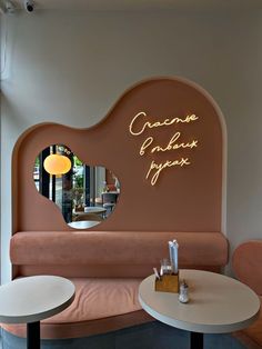 the interior of a restaurant with pink booths and round tables, mirrors on the wall