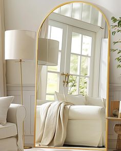 a living room filled with furniture and a large gold framed mirror on the wall next to a white couch