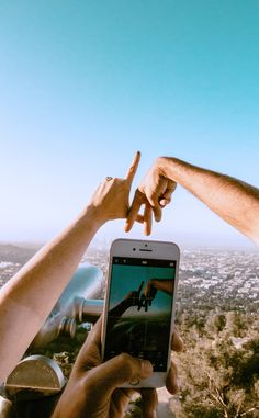 two people reaching out their hands to touch something on a cell phone in the air