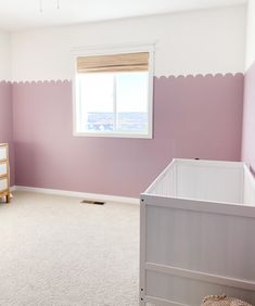 a baby's room with pink walls and white carpet