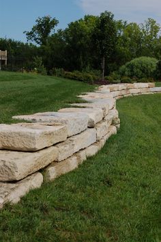 a stone wall in the middle of a grassy field