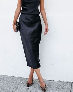 Perfect for any occasion, this black midi skirt combines comfort and style effortlessly! The Muse By Magnolia Black Satin Midi Skirt boasts an elastic waistband for a customizable fit and is made of 100% polyester for a luxurious feel. Style it with the matching satin cami along with some strappy heels and a matching clutch for an elevated workwear look! Black Formal Skirt For Summer, Solid Color Midi Pencil Skirt For Party, Chic Black Pencil Skirt For Party, Party Midi Pencil Skirt In Specific Color, Party Midi Pencil Skirt, Black Midi Length Dresses With Lined Skirt, Black Lined Maxi Skirt For Work, Elegant Black Midi Length Skirt, Chic Lined Maxi Skirt For Date Night