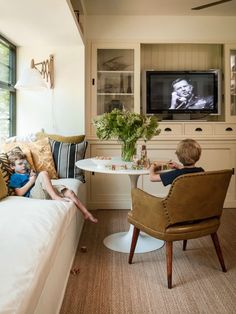 a living room filled with furniture and a flat screen tv mounted on the wall above a table