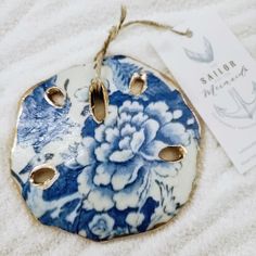 a blue and white flowered ceramic ornament with two holes in the middle