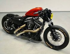 a red and black motorcycle is parked in a white room with no people on it