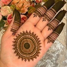 a hand with henna on it and flowers in the background