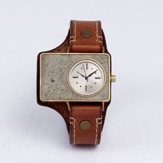 The Mason Watch was crafted for individuals with an eye for sophisticated resilience. Its brick design was expertly filled with concrete and boasts a quartz movement behind a satin nickel dial. The light-weight (1.6oz) brass case and two-toned leather cuff add a rugged touch of style and durability. Due to the handmade nature of the creation, each piece may have slight variations. All items come with free movement repair and leather maintenance for the life of the product. Case Size 25mm x 40mm Rectangular Leather Chronograph Watch, Leather Chronograph Rectangular Watch, Rectangular Dial Quartz Watch, Leather Watch With Metal Dial As Gift, Leather Watches With Metal Dial As Gift, Leather Analog Display Watch As Gift, Leather Analog Watch As A Gift, Vintage Leather Watch With Metal Dial, Masonic Watches