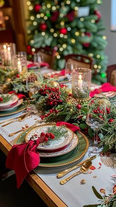 a christmas table setting with candles and greenery