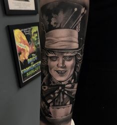 a man's arm with a black and white tattoo design on it, featuring a woman in top hat