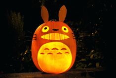 a carved pumpkin with an image of totoro on it's face in the dark