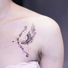 a woman's chest with an arrow and wings tattoo on her left side shoulder