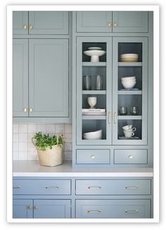 a kitchen with blue cabinets and white dishes on the counter top, along with a potted plant