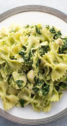 a white plate topped with pasta and broccoli covered in pesto on top of a table