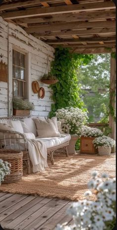 the porch is covered with white flowers and wicker furniture