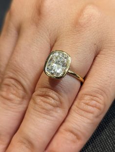 a close up of a person's hand with a diamond ring on their finger