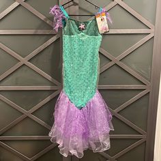 a little mermaid costume hanging on a door hanger in front of a metal wall