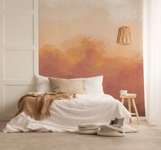 a bedroom with a pink wall and white bed in the foreground is a pair of slippers on the floor