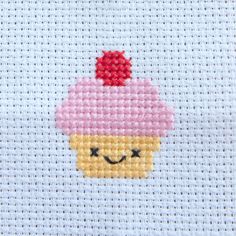 a cross - stitch picture of a cupcake with a smiling face on it's side