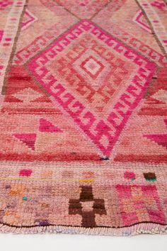 an old rug with pink and brown designs on it's edges, sitting on top of a white surface