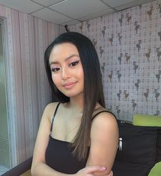 a woman sitting in front of a mirror with her arms crossed and looking at the camera